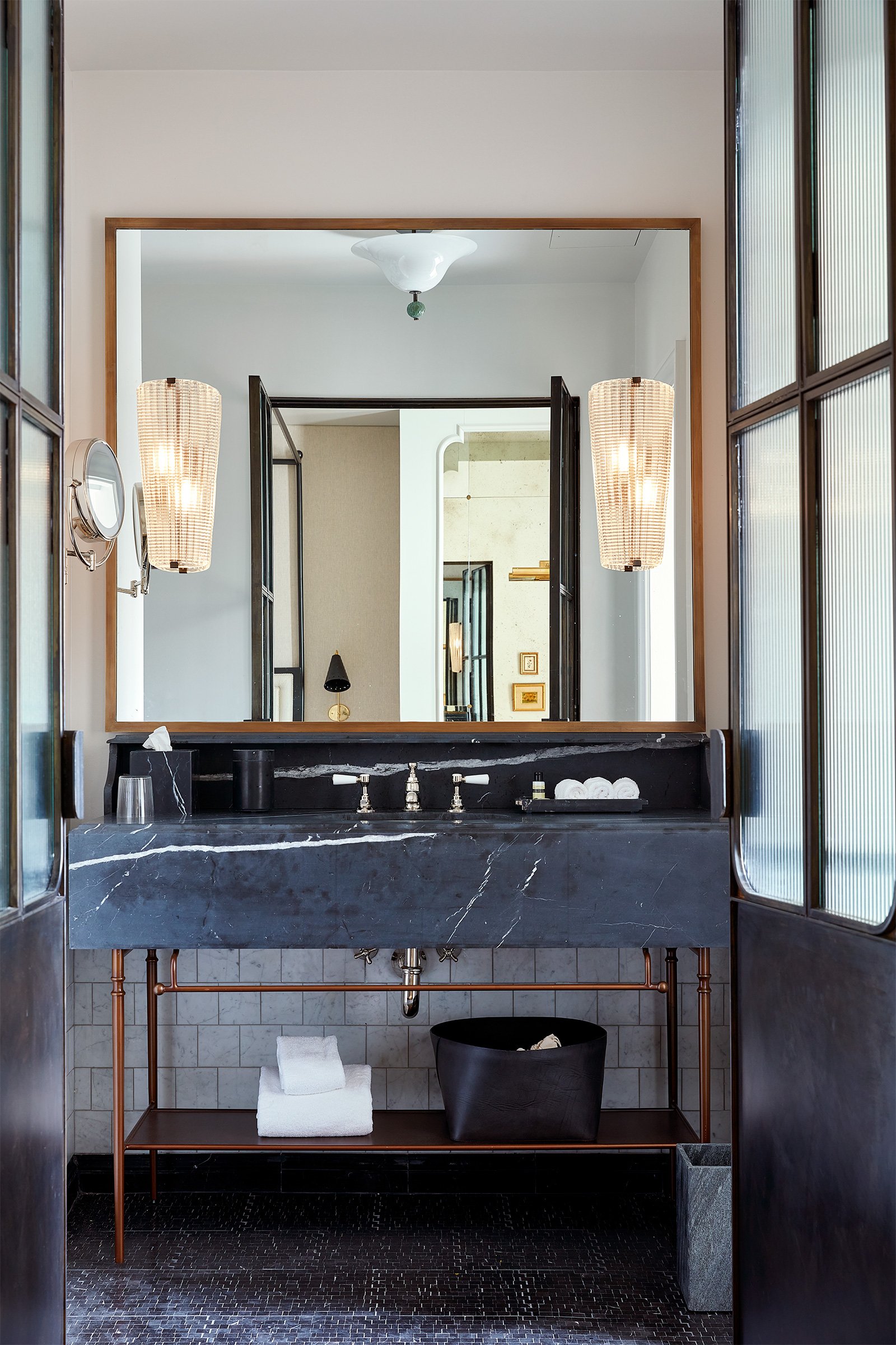 A black stone vanity in a black marble tiled bathroom