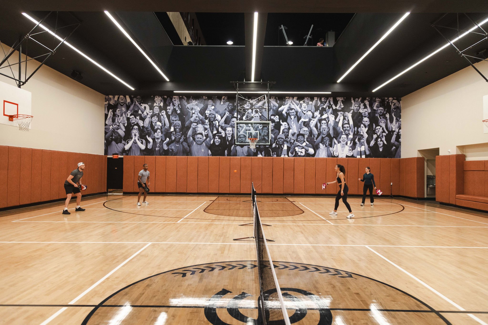 A foursome playing pickleball on a full size NBA basketball court