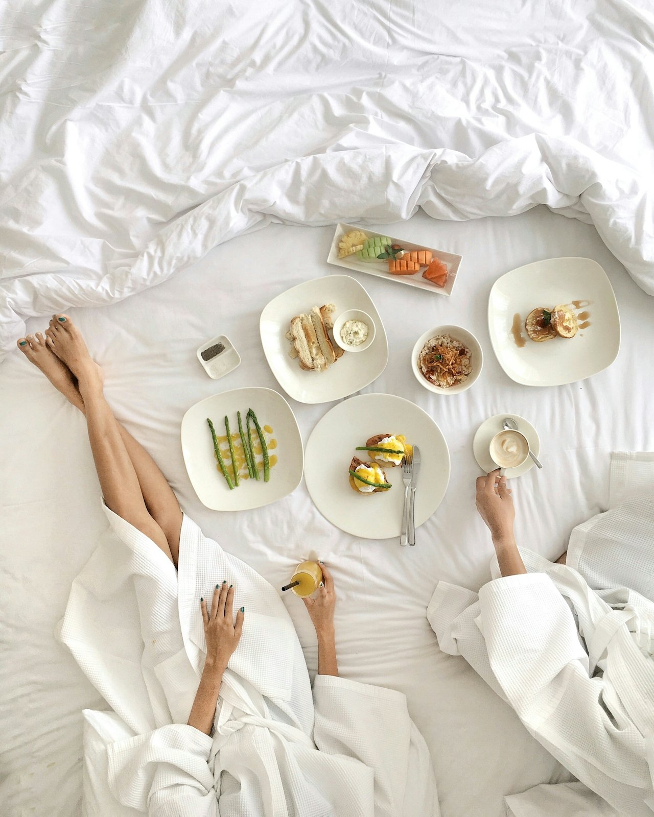 Two unidentifiable people overhead in bed with room service.