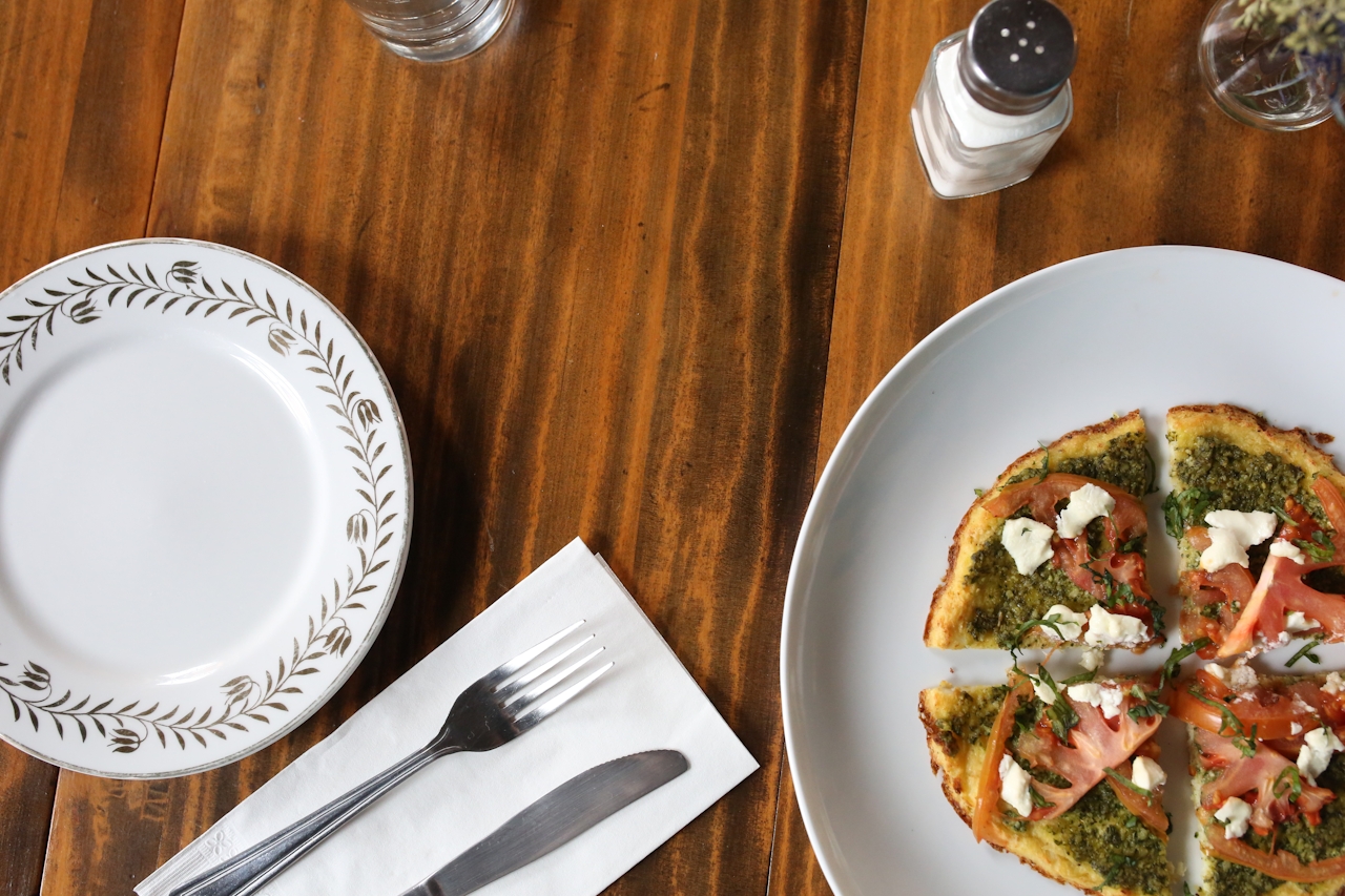 An overhead shot of a flatbread pizza on a wood table.