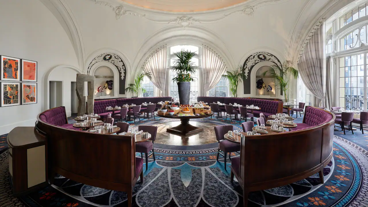 A round room with an arched window and dining tables.